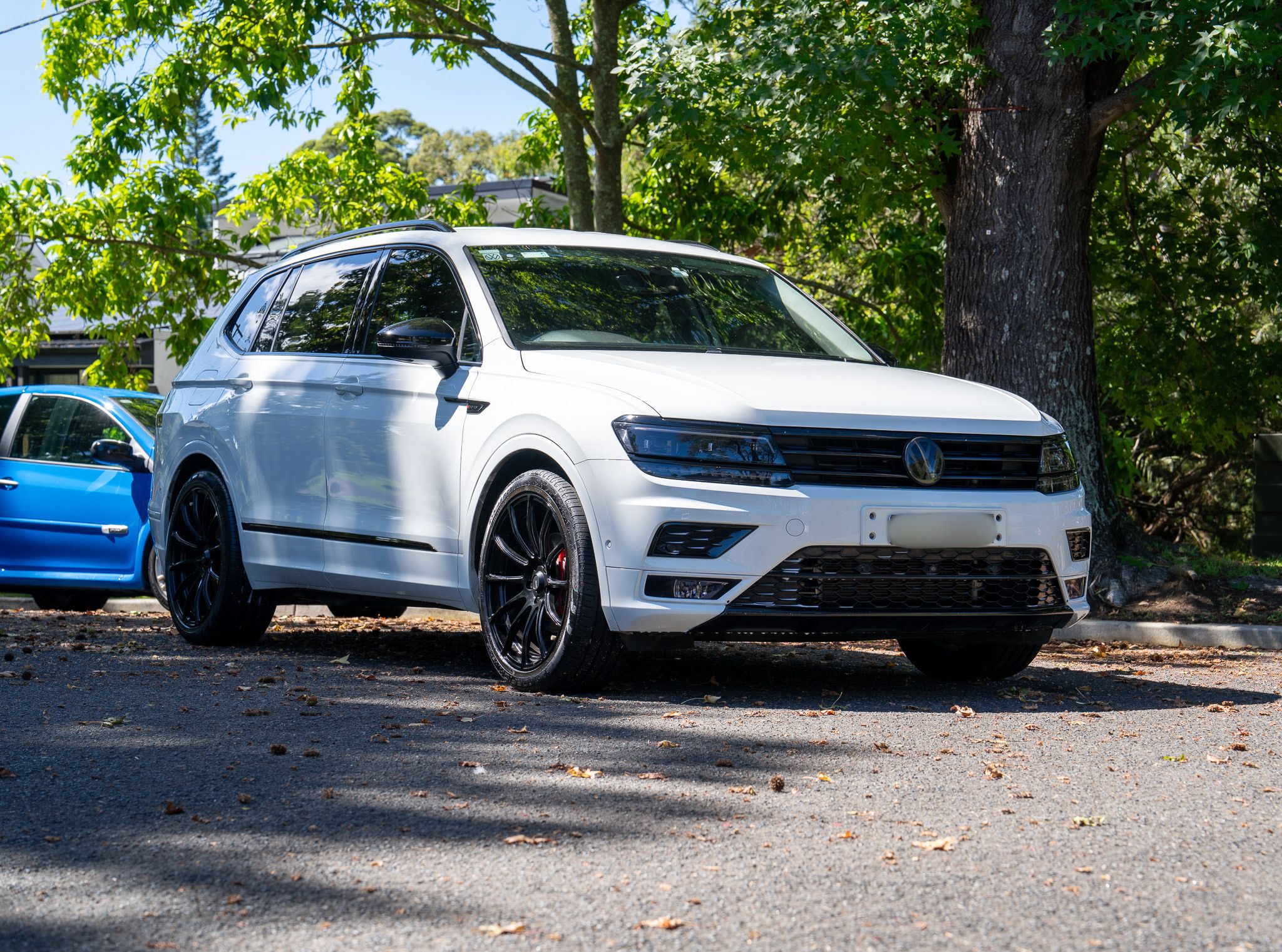 White Volkswagen Tiguan after a detail, parked under trees