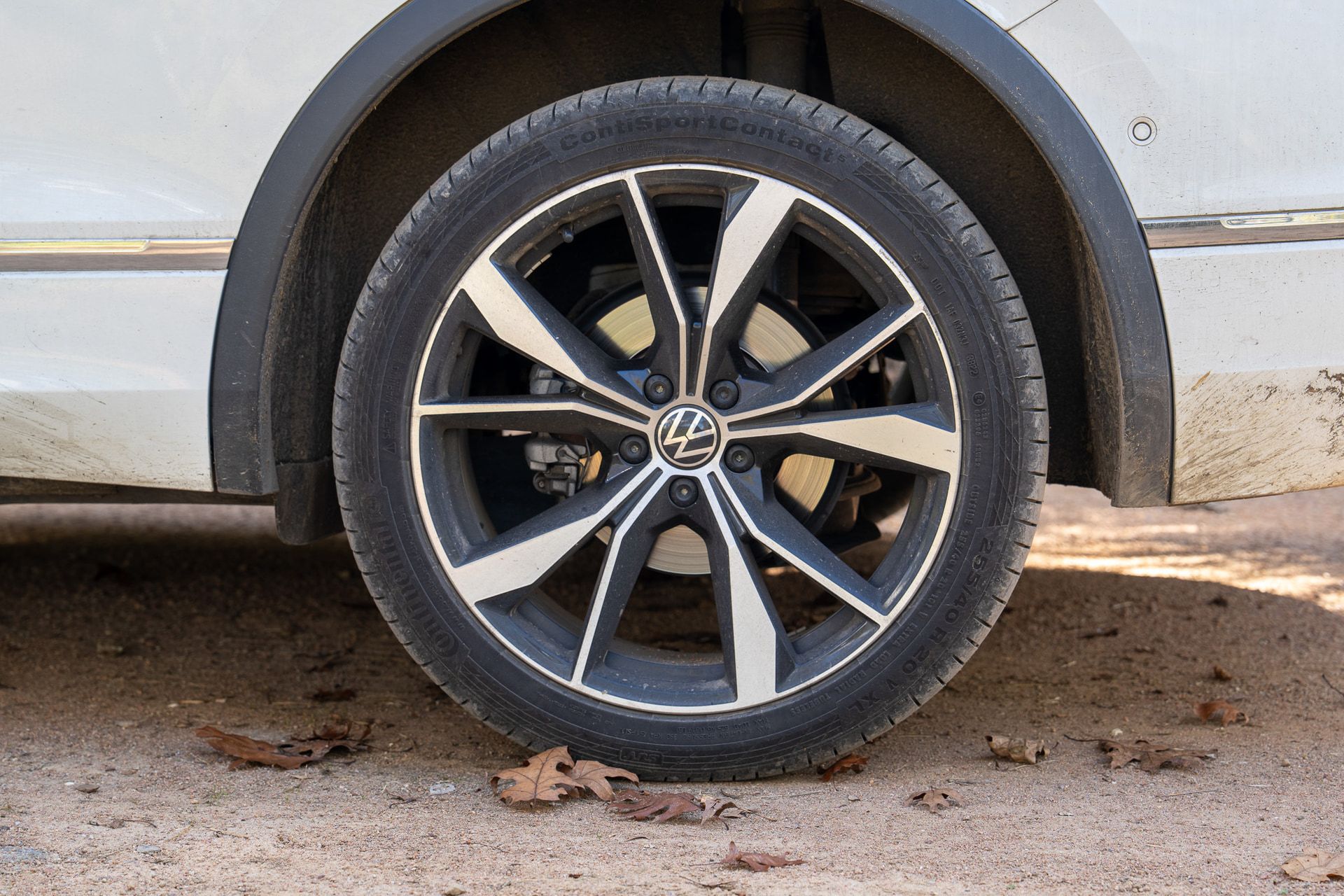 Before: a white Volkswagen Tiguan's rear wheel dull with dust and grime, with mud splashed on the bumper behind it